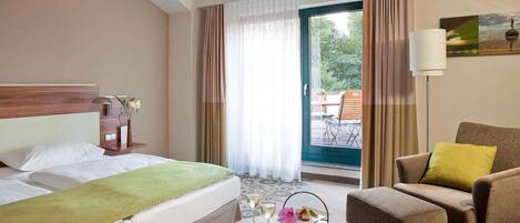 A hotel room with a bed, a seating area with a table, and a view through a glass door.
