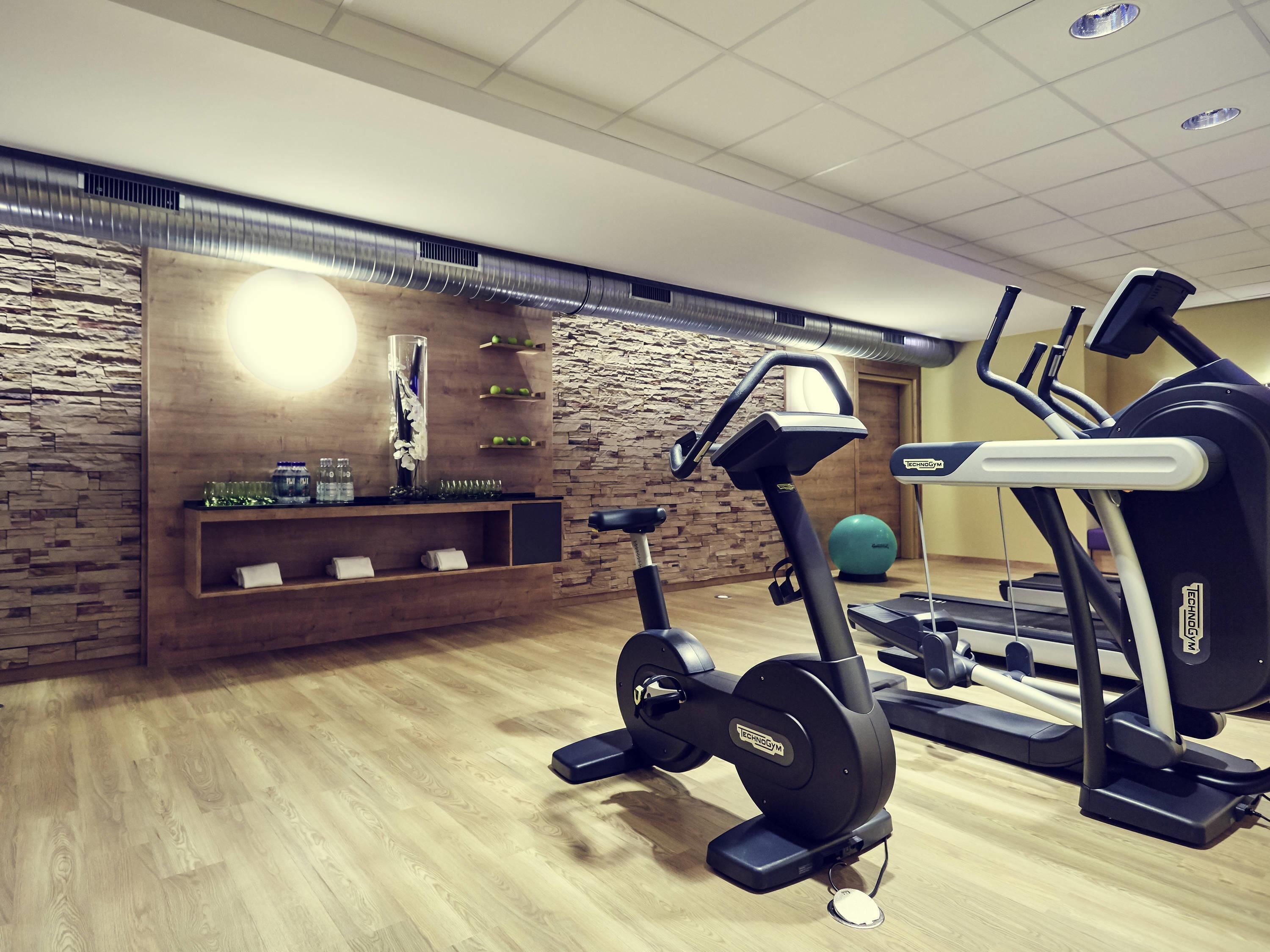A gym with exercise equipment, a wooden wall with shelves, and a stone wall.
