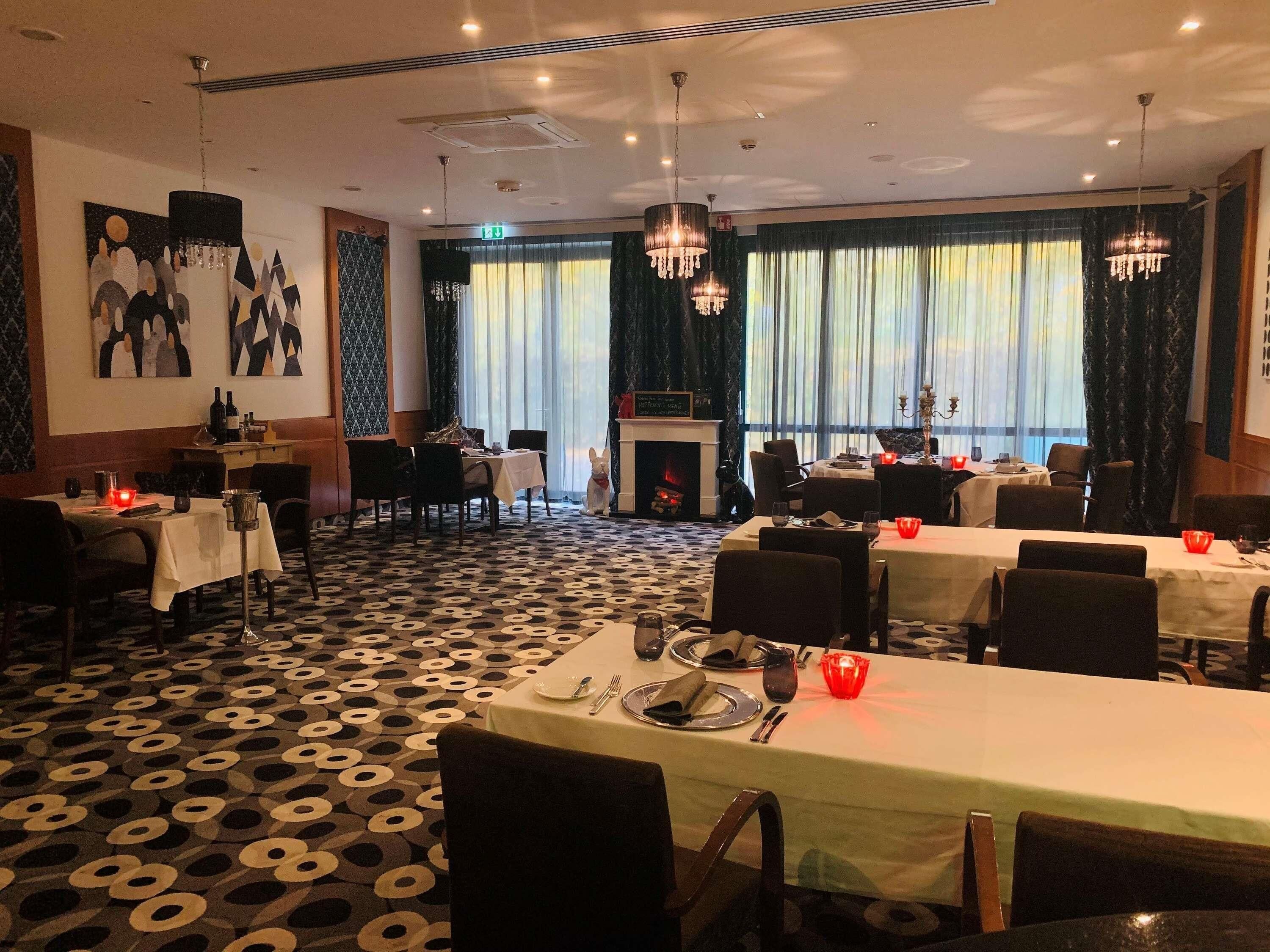 A dining area with tables set for service, a fireplace, and artwork on the walls.