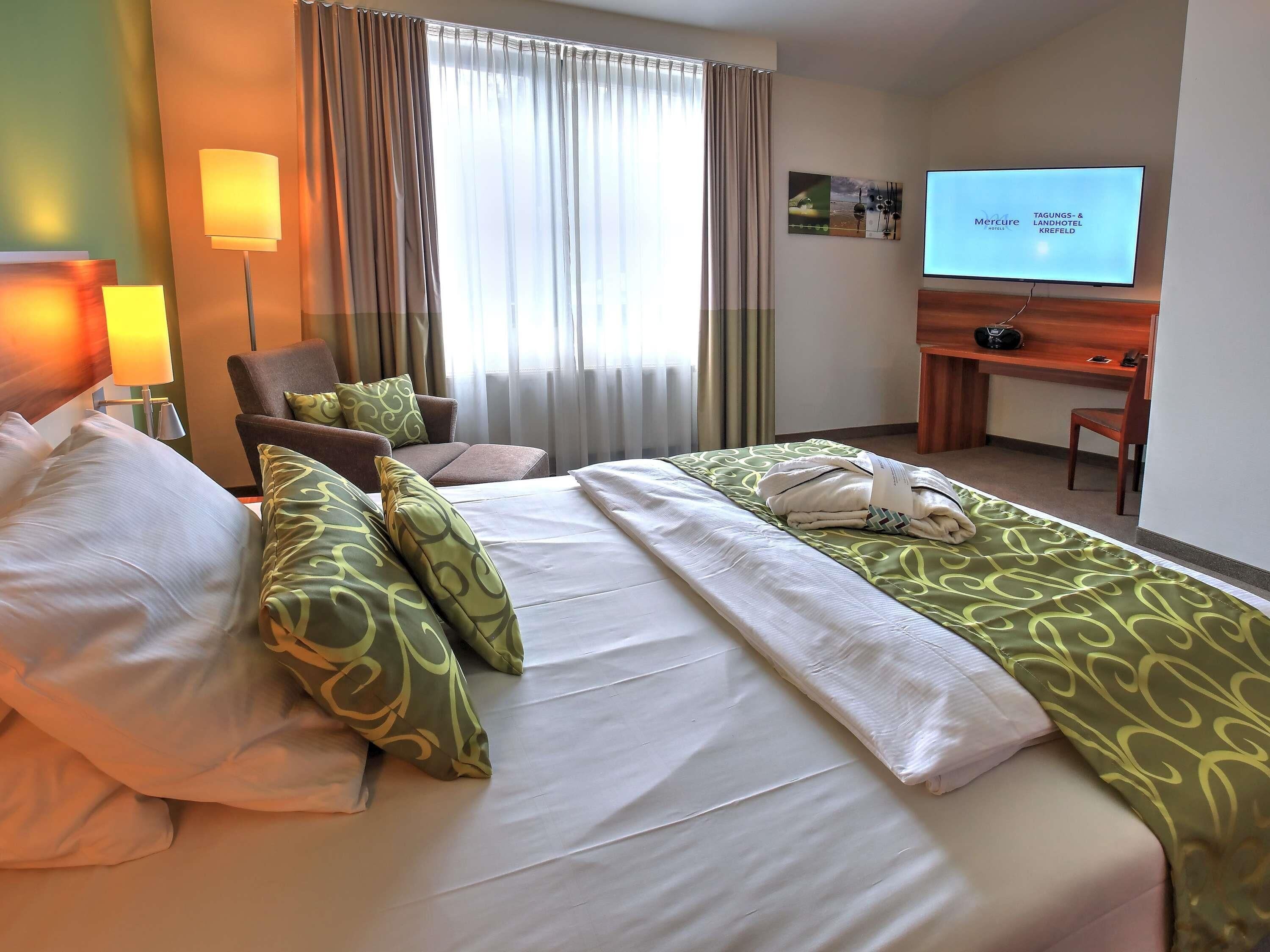 Una habitación de hotel con cama, escritorio, televisión y una silla.