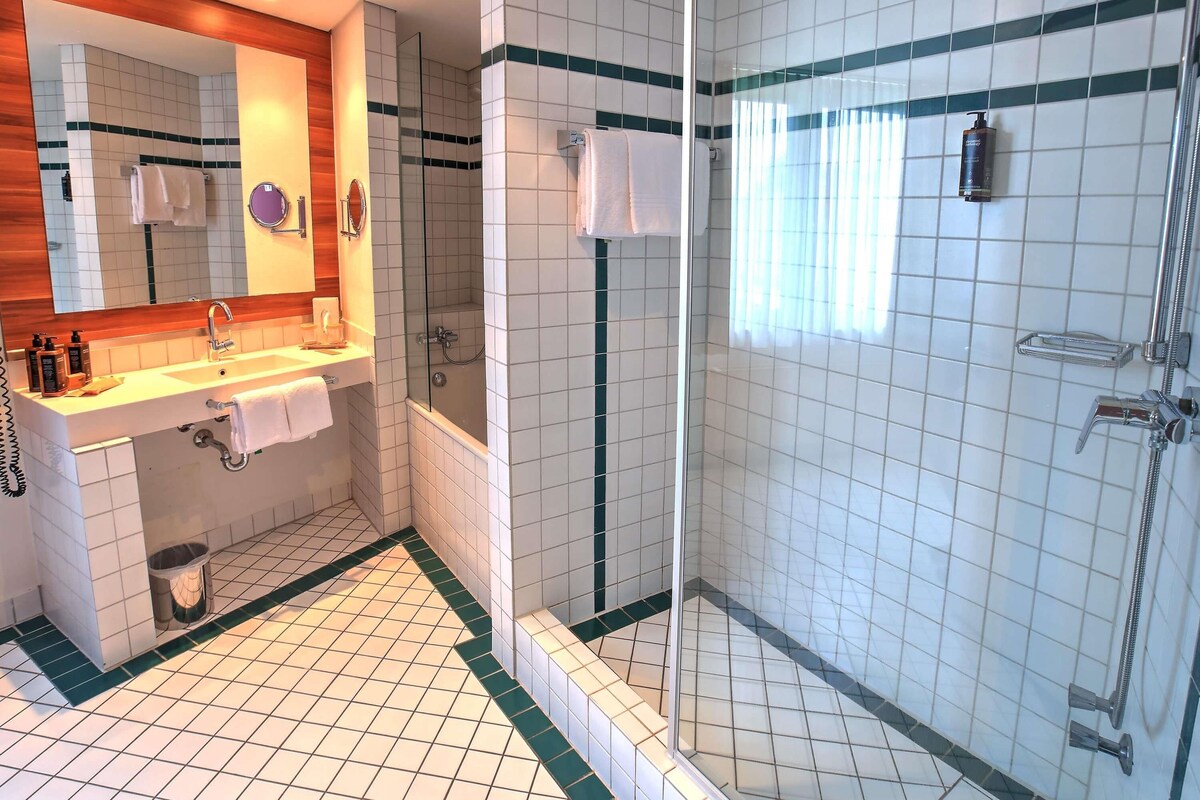 Een badkamer met een wastafel, spiegel en douche.