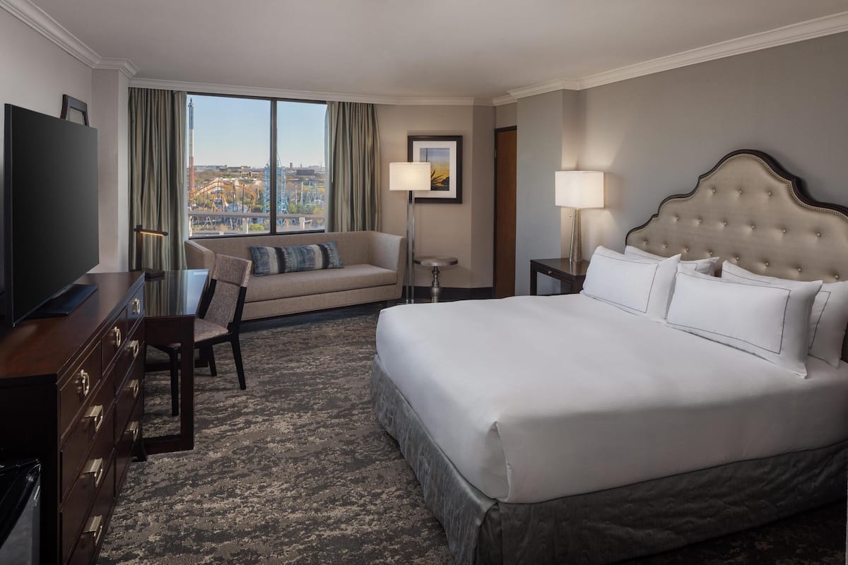 A hotel room with a large bed, a sofa, a TV, and a desk.