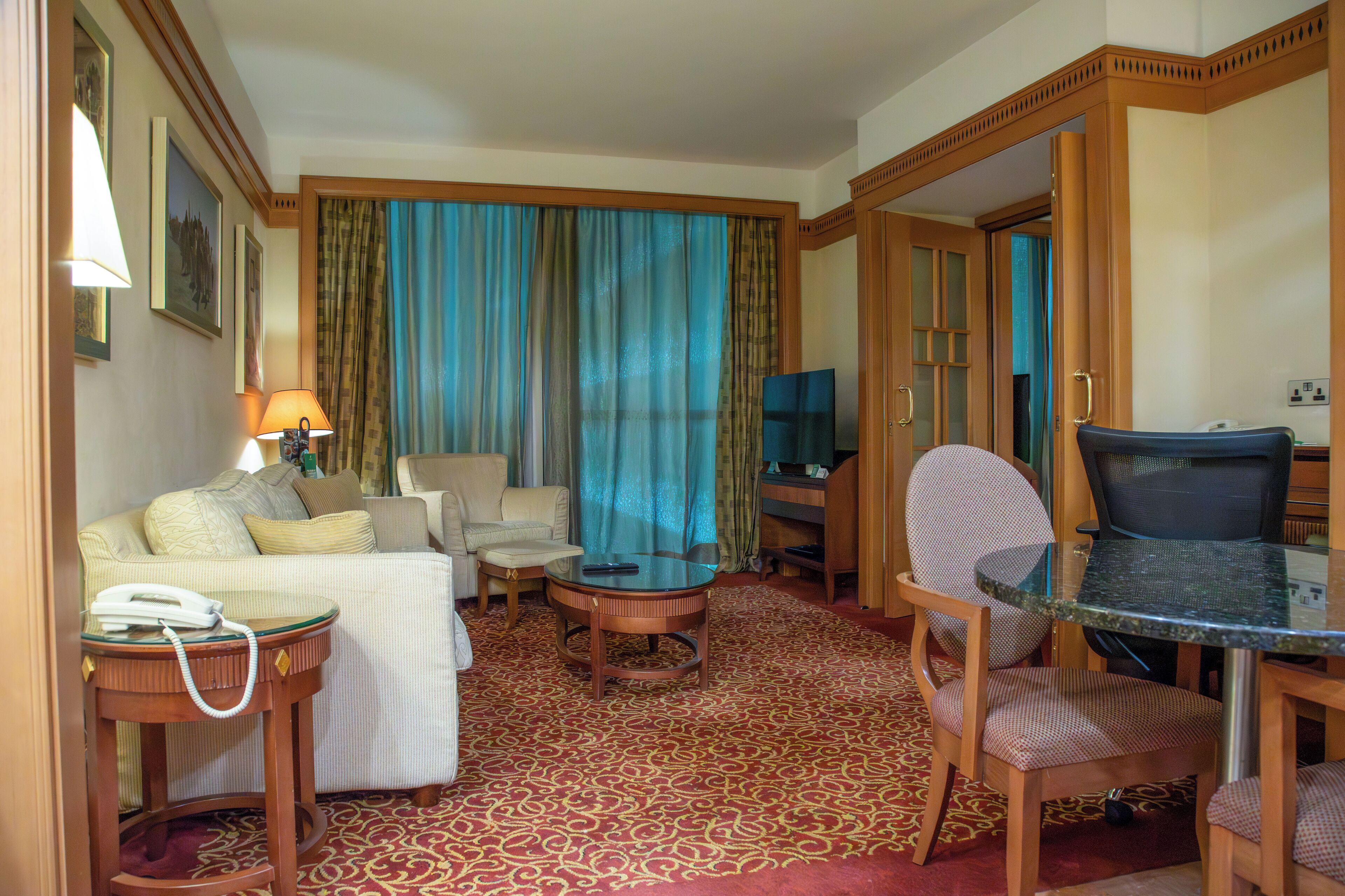 Une chambre d’hôtel comprenant un canapé, un fauteuil, une table ronde et un bureau avec une chaise.