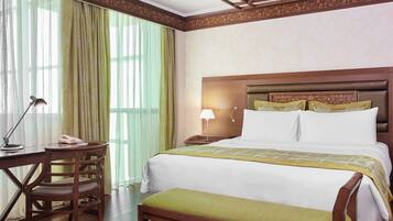 A hotel room with a wooden bed, a desk with a lamp, and a chair.