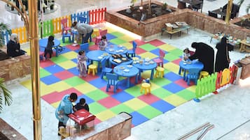 Relax and play in our vibrant play zone, featuring colorful interlocking foam mats and comfortable seating areas.
