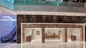 A hotel lobby with a reception desk, marble flooring, and a glass railing overlooking a lower level. - Holiday Inn Kuwait Al Thuraya City by IHG (Farwaniya)