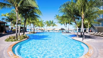 A swimming pool surrounded by palm trees and lounge chairs.