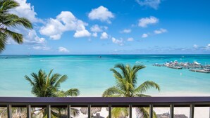 A beach view with clear turquoise water, a dock with boats, and palm trees. - Holiday Inn Resort Aruba - Beach Resort & Casino by IHG (Noord)