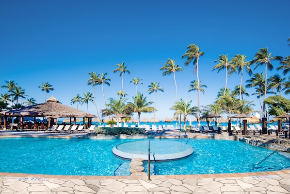 Une piscine avec des chaises longues et des palmiers.