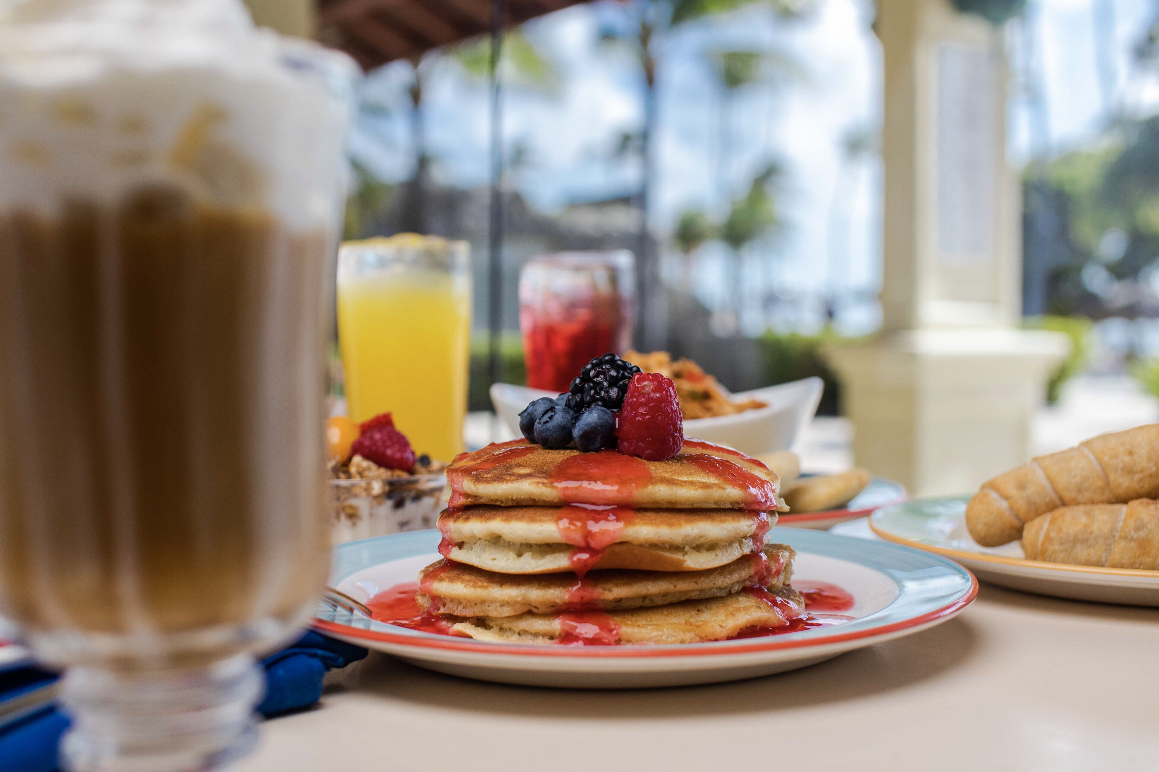 Colazione con pancake, frutti di bosco e croissant su un tavolo.