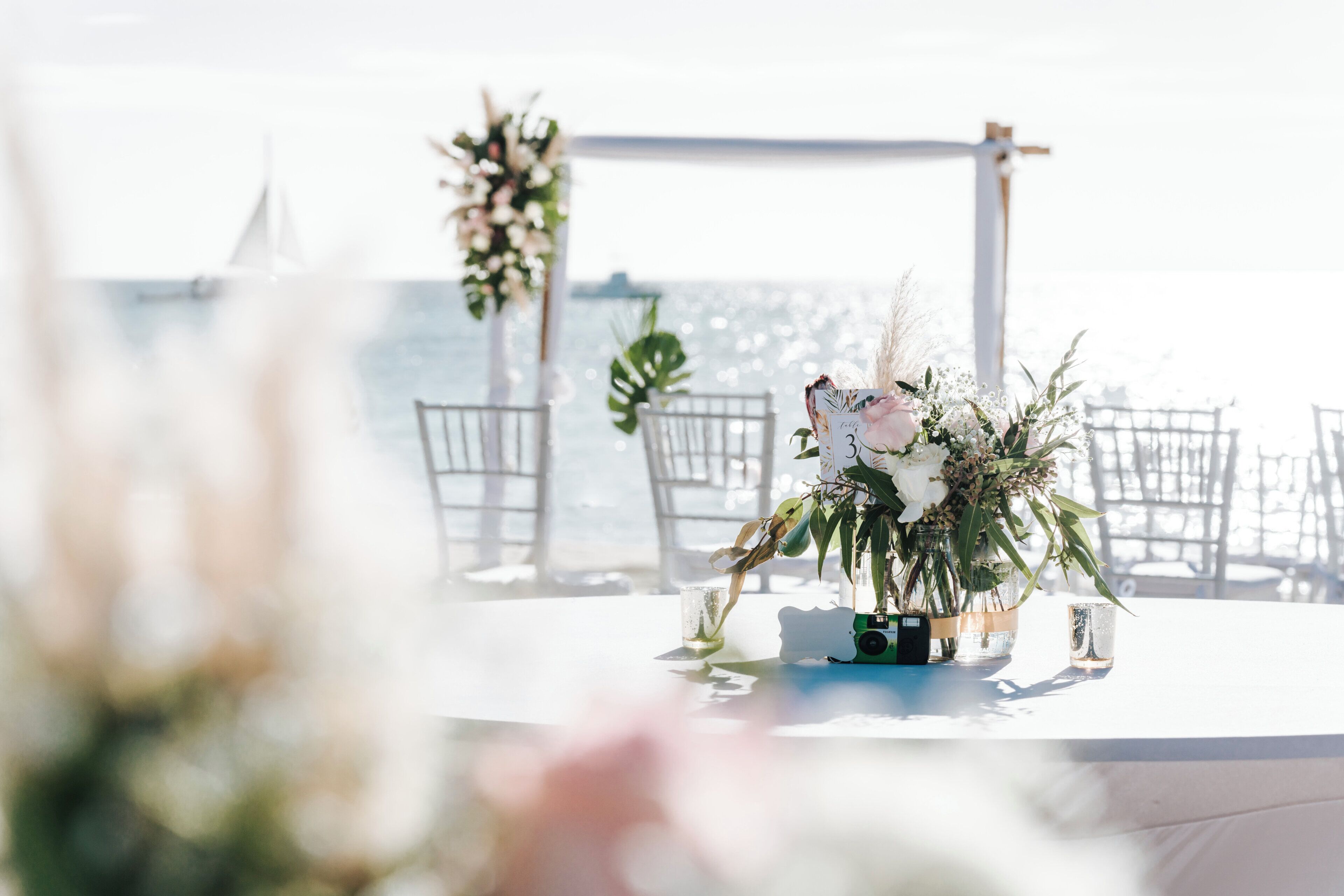A table set for a wedding ceremony with floral arrangements and a microphone.