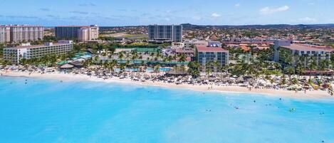 A coastal resort with beachfront accommodations, a pool area, and a view of the surrounding landscape.