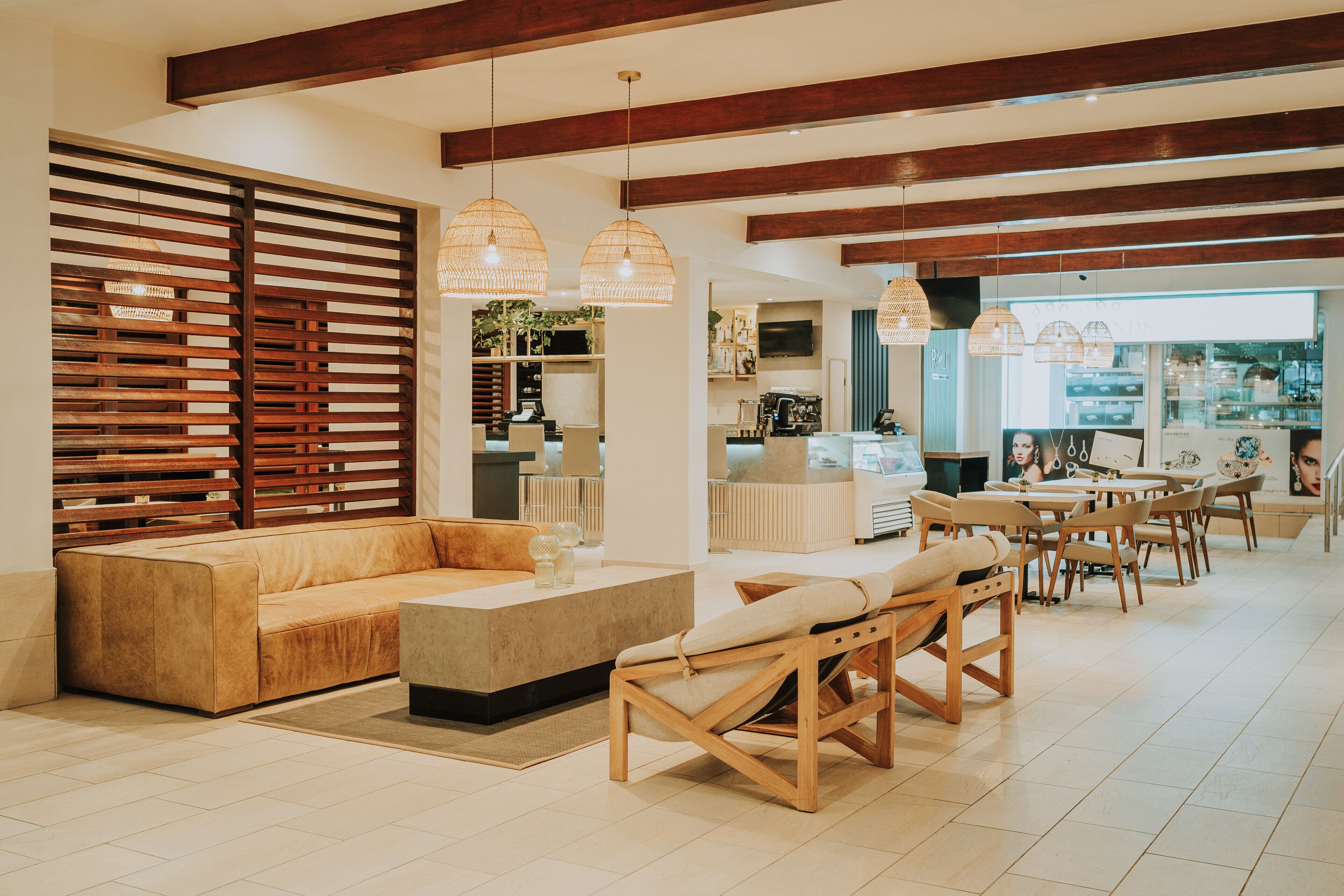 A modern living room with a sofa, chairs, and a coffee table. There is a kitchen area in the background with a TV and a counter.