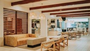 Una sala de estar moderna con un sofá, sillones y una mesa de centro. Se ve un área de cocina al fondo, con un televisor y una encimera.