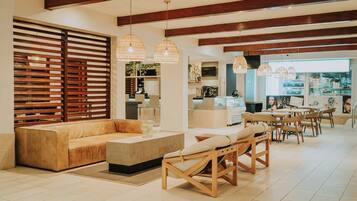 A modern living room with a sofa, chairs, and a coffee table. There is a kitchen area in the background with a TV and a counter.