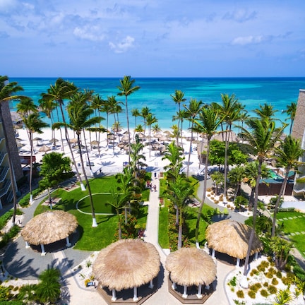 A resort with multiple buildings, a beach, and palm trees.
