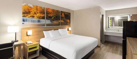 A hotel room with a bed, desk, chair, nightstand, and a large window.