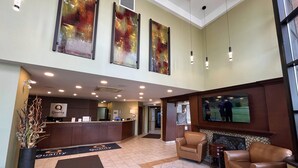 Un hall de hotel con mostrador de recepción, zona de estar, obras de arte y una pantalla de televisión.