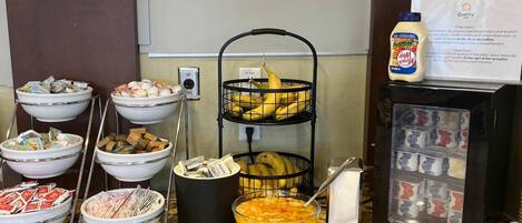 Montaje de bufé con diversos alimentos y dispensador de bebidas.