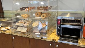 Una vitrina de panadería con distintos productos horneados y un horno tostador industrial.