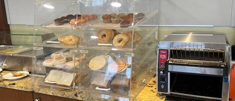 Een bakkerijdisplay met diverse gebakjes en een commerciële broodroosteroven.
