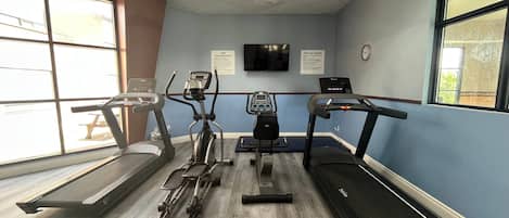 Un gimnasio con cintas de correr, elípticas y bicicletas estáticas.