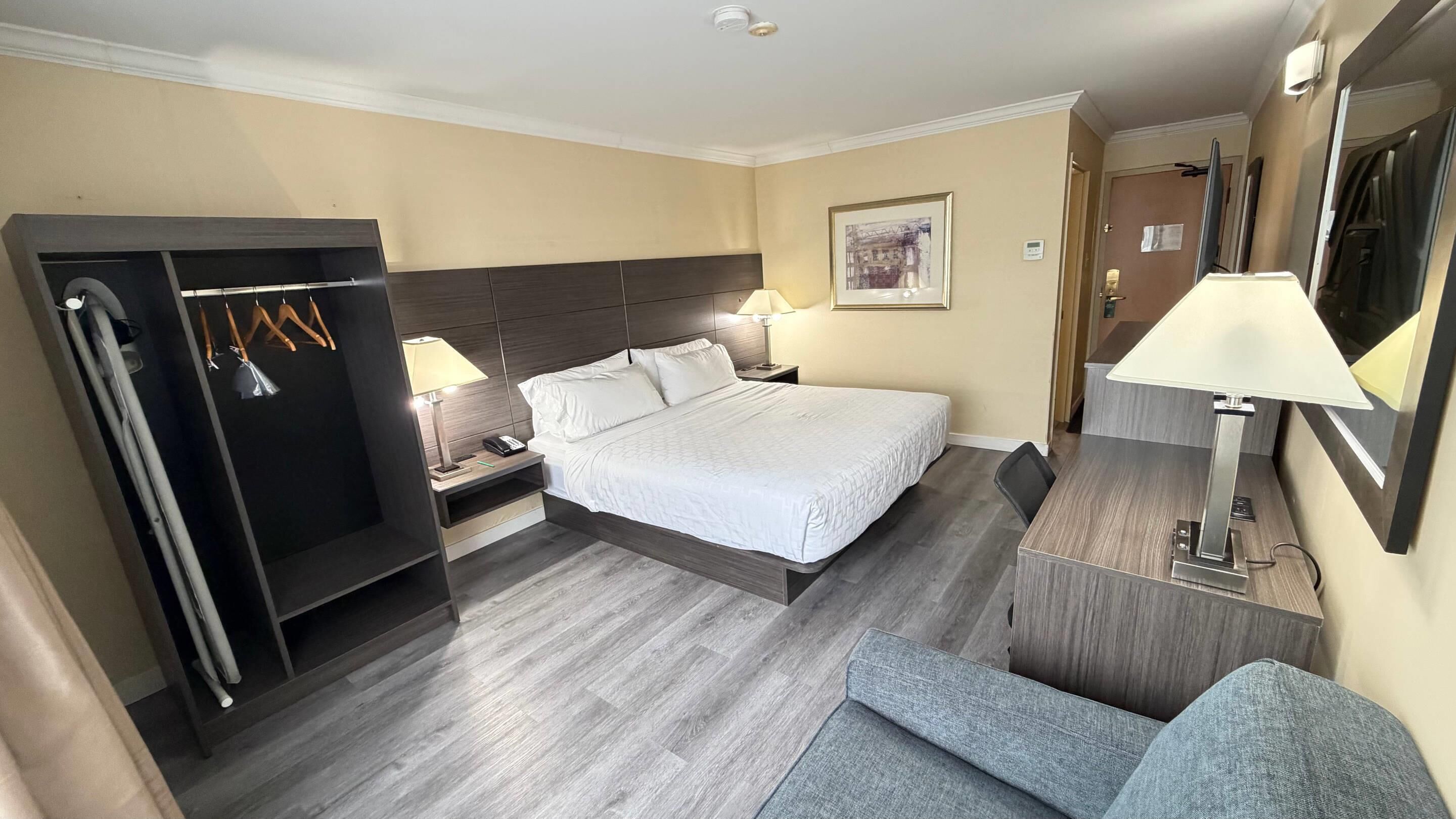 Een hotelkamer met een bed, nachtkastjes, een bureau, een stoel, een kledingkast en een spiegel.