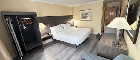 Een hotelkamer met een bed, nachtkastjes, een bureau, een stoel, een kledingkast en een spiegel.