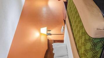 A compact hotel room with a bed, a small table, a chair, and a window with blinds.