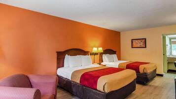 A hotel room with two beds, a chair, and a desk.