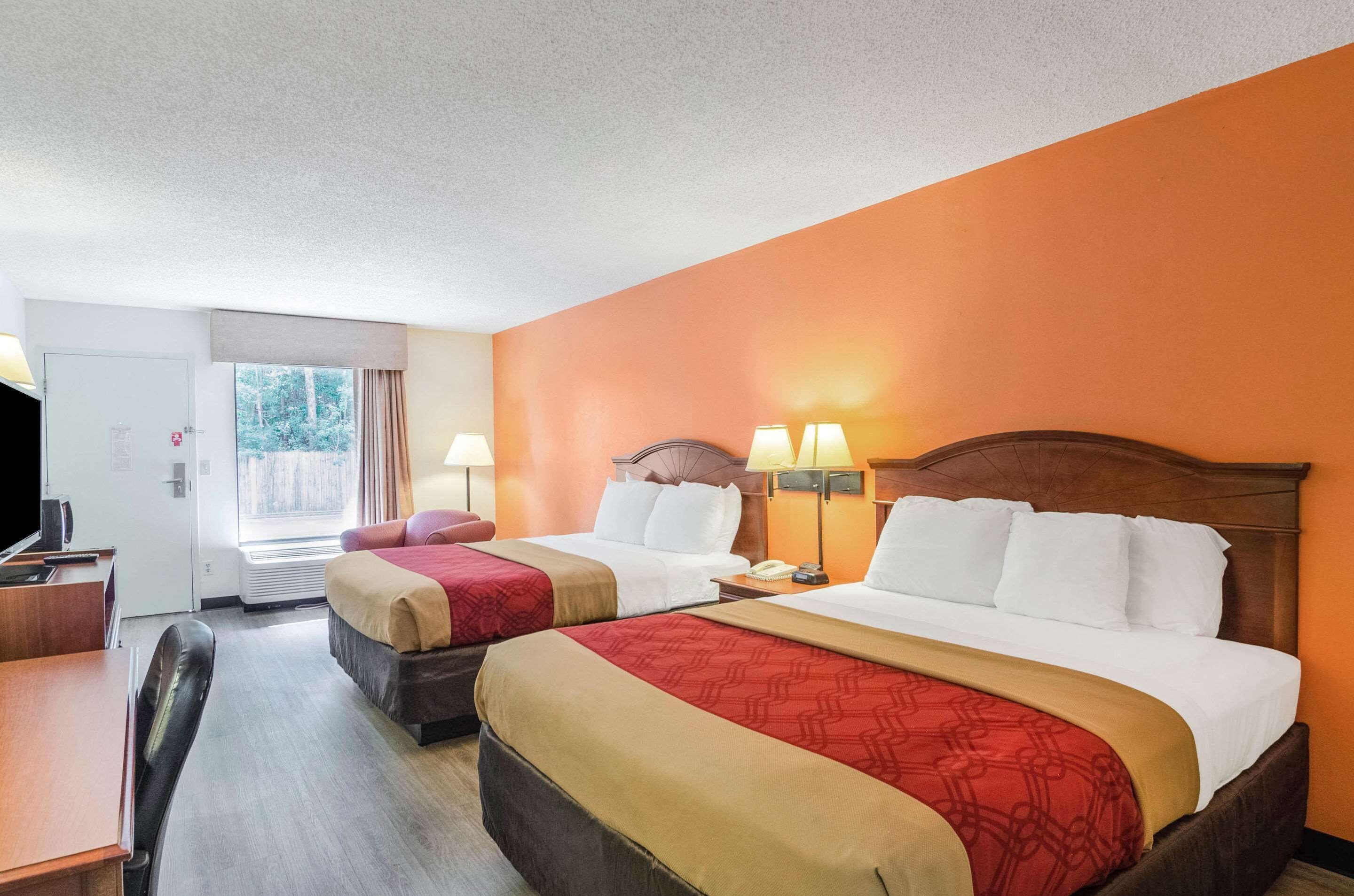 A hotel room with two beds, a desk, and a television.
