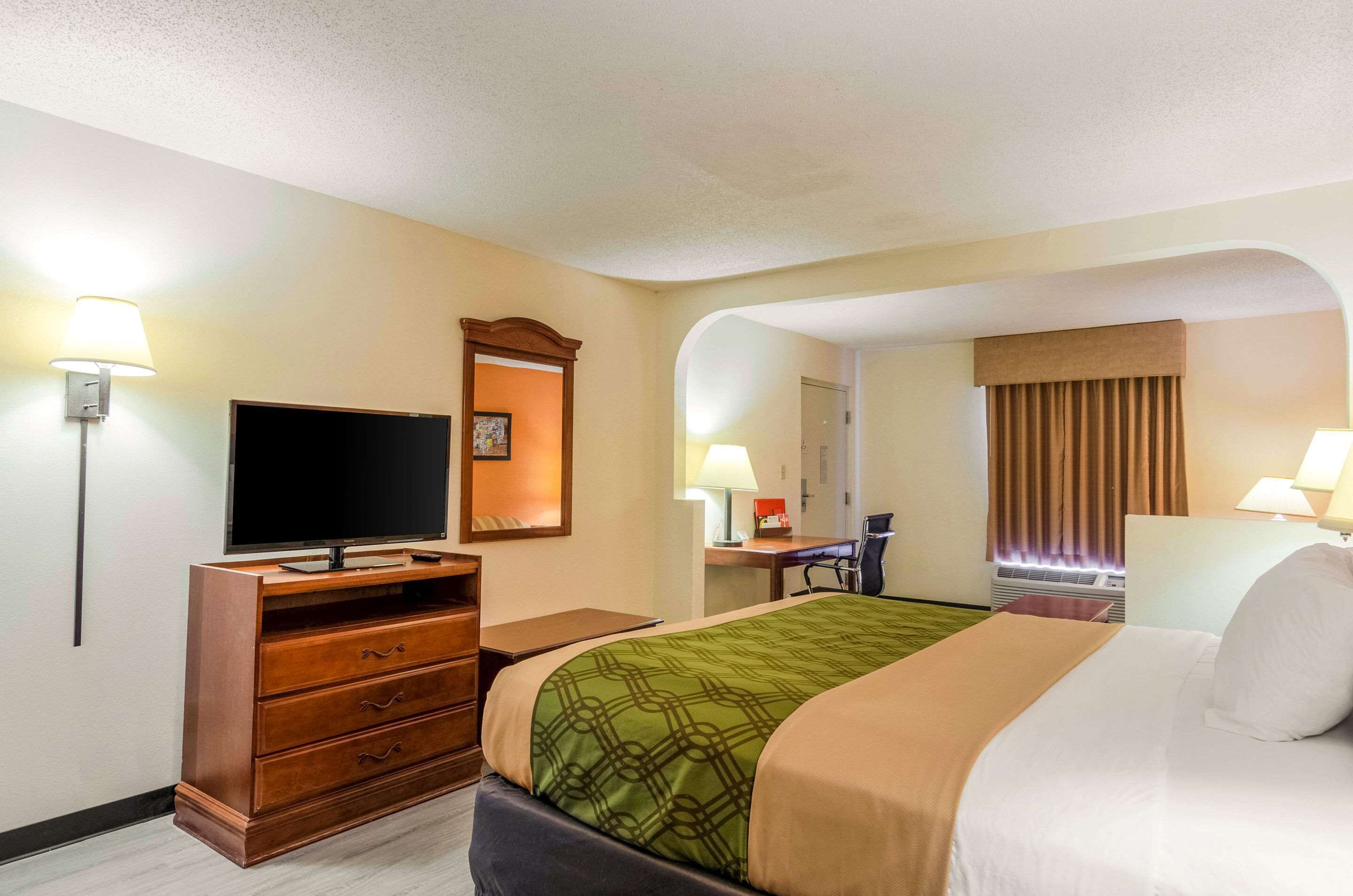 A hotel room with a bed, a TV, a desk, and a chair.