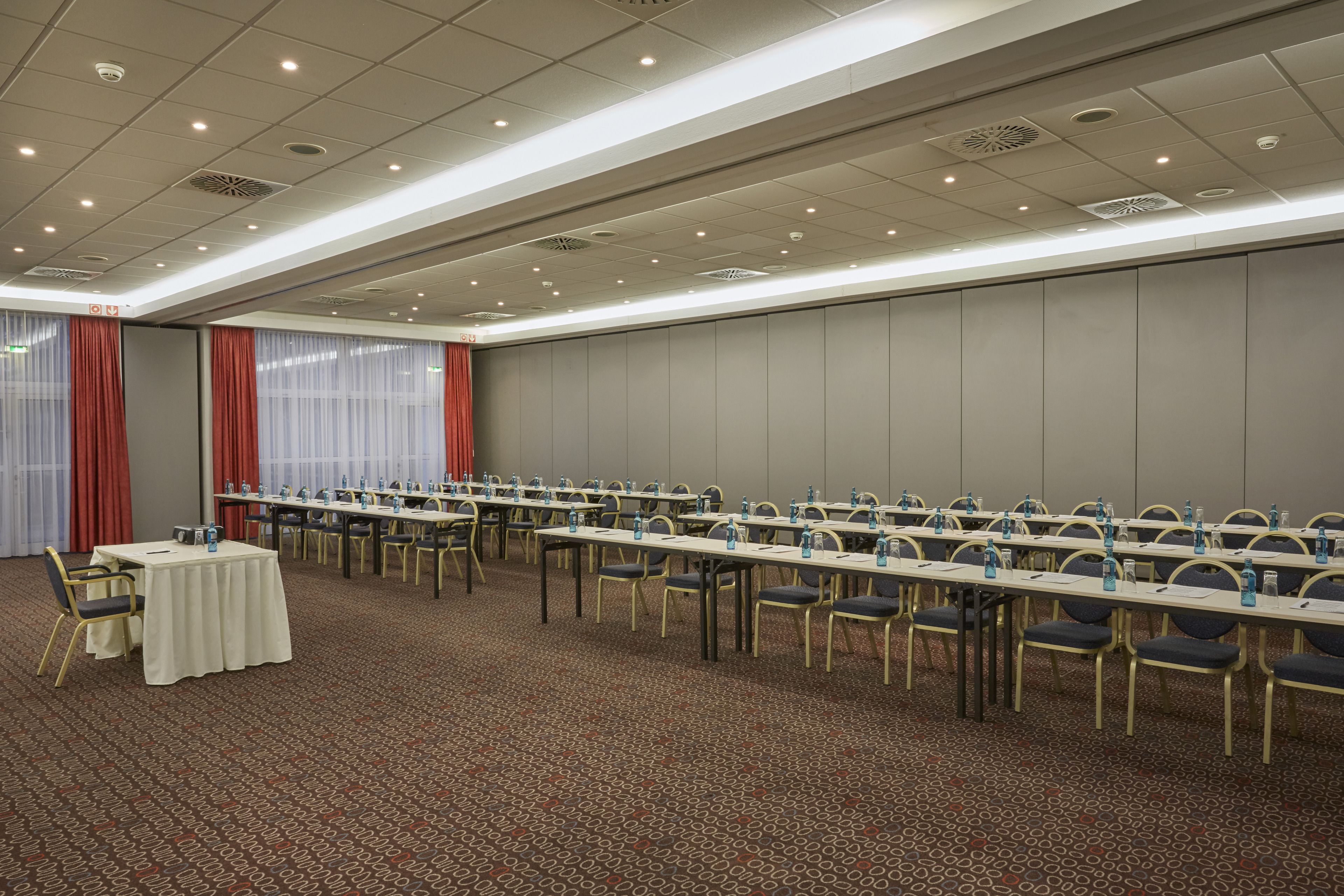 A conference room with long tables and chairs, equipped with water bottles and nameplates.
