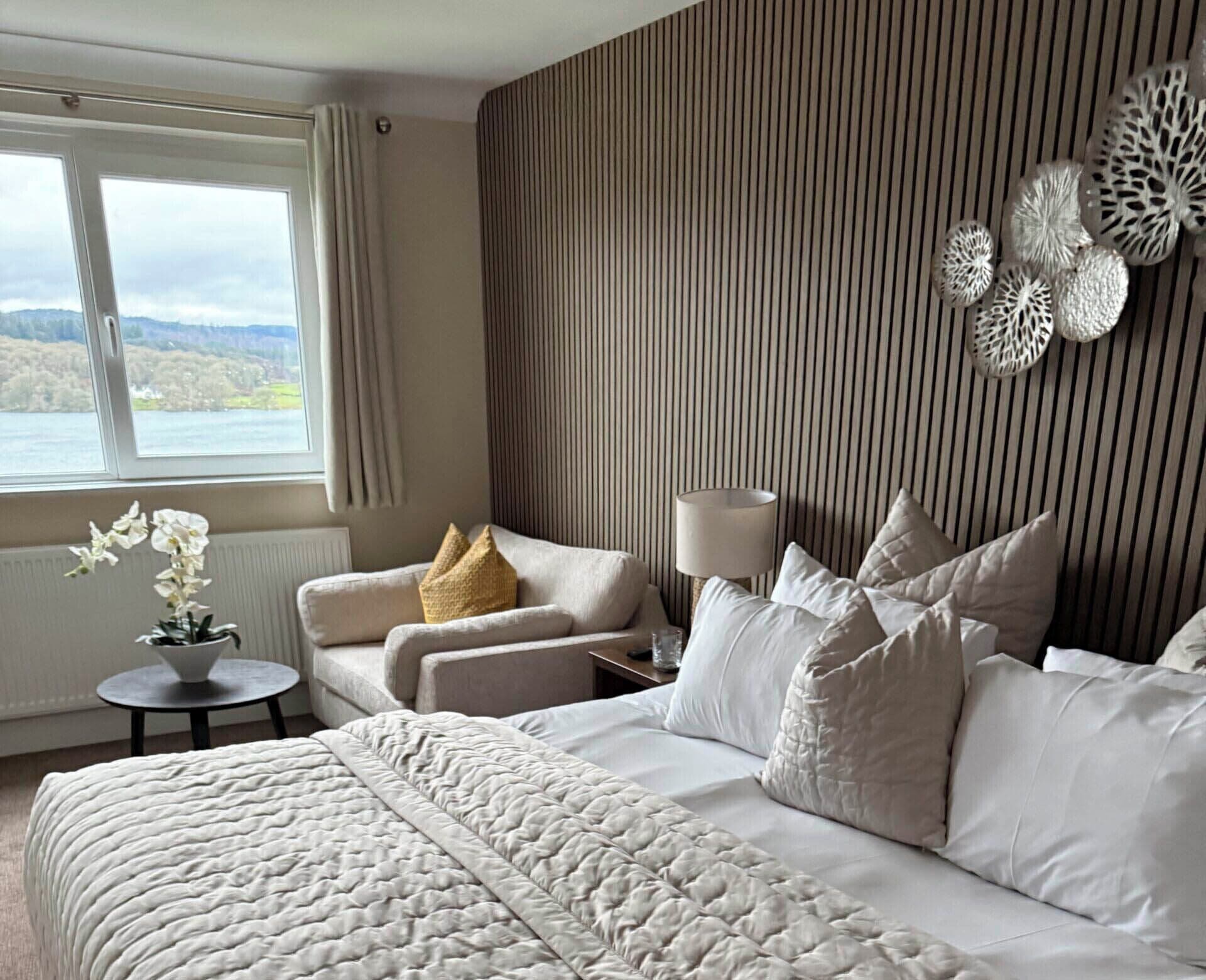 Un dormitorio con cama, una silla, una lámpara y vistas al exterior.