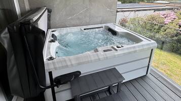 A hot tub on a wooden deck with a view of a hillside.