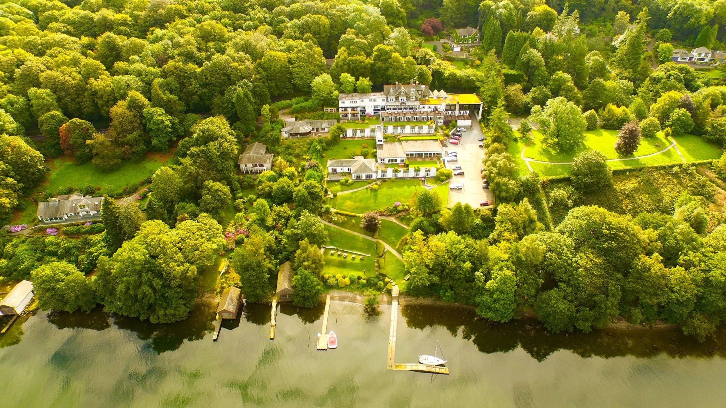 An aerial view of a large estate with multiple buildings, a dock, and a lake.