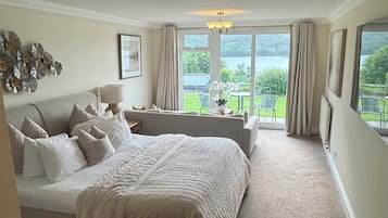 Un dormitorio amplio con una cama grande, una zona de estar y vistas a un lago.