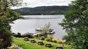 Vista al lago con mesas de picnic y un velero.