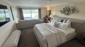 Quarto com uma cama grande, escrivaninha, cadeira e vista para o exterior.