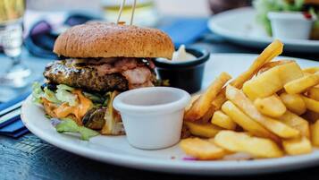 A plate with a burger, fries, and a small cup of sauce.