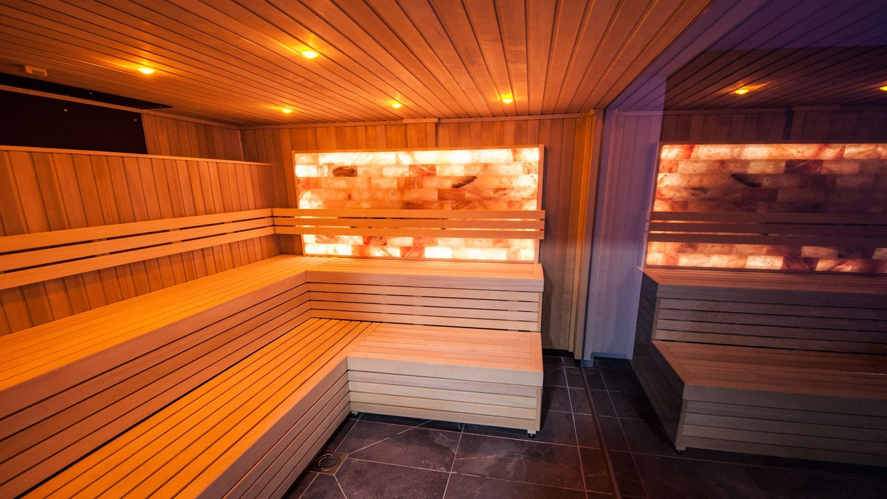 A sauna with wooden benches and a stone wall.