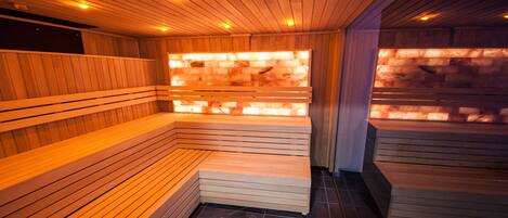 A sauna with wooden benches and a stone wall.