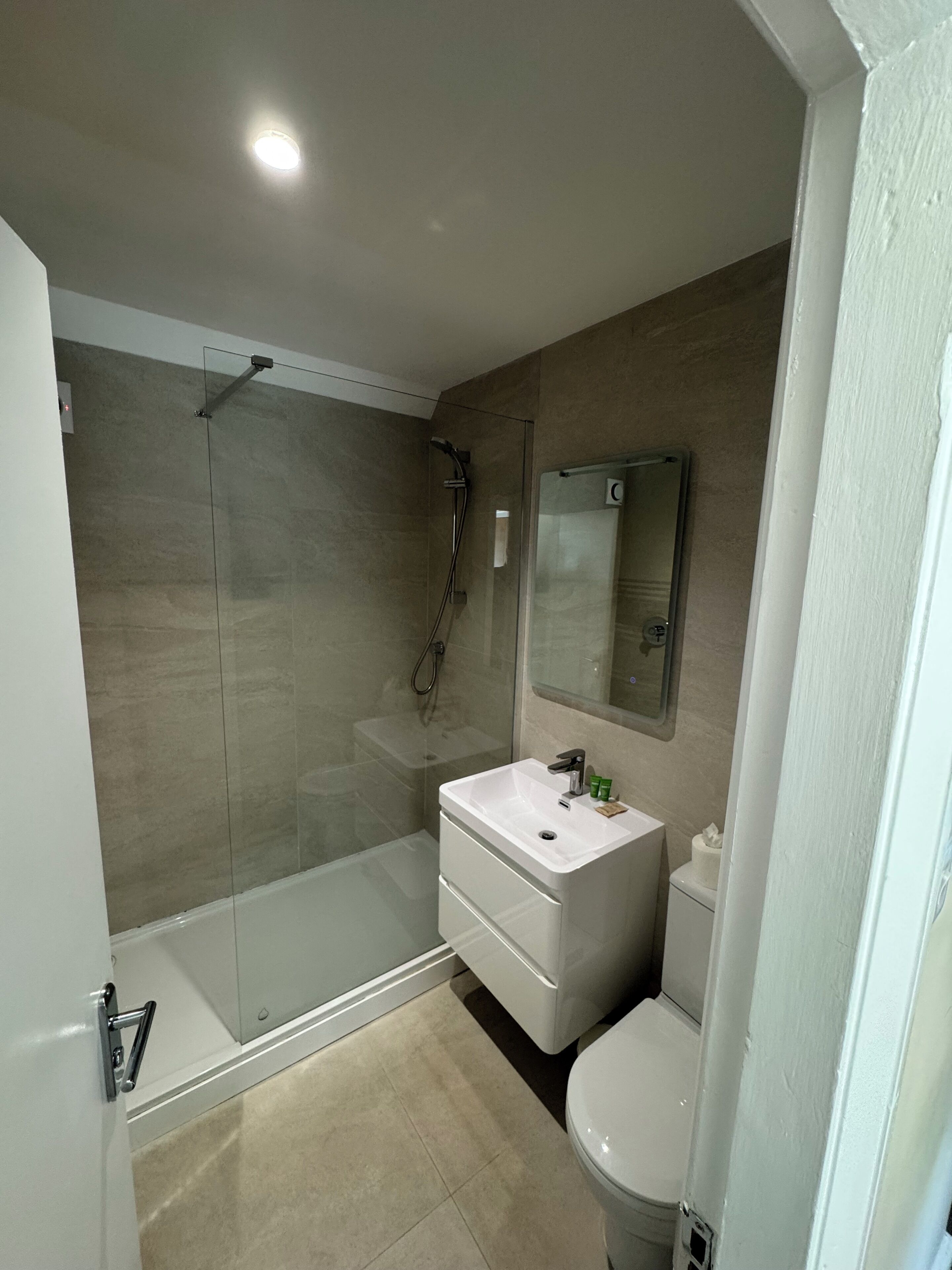 A modern bathroom with a glass-enclosed shower, a white vanity with a mirror, and a toilet.