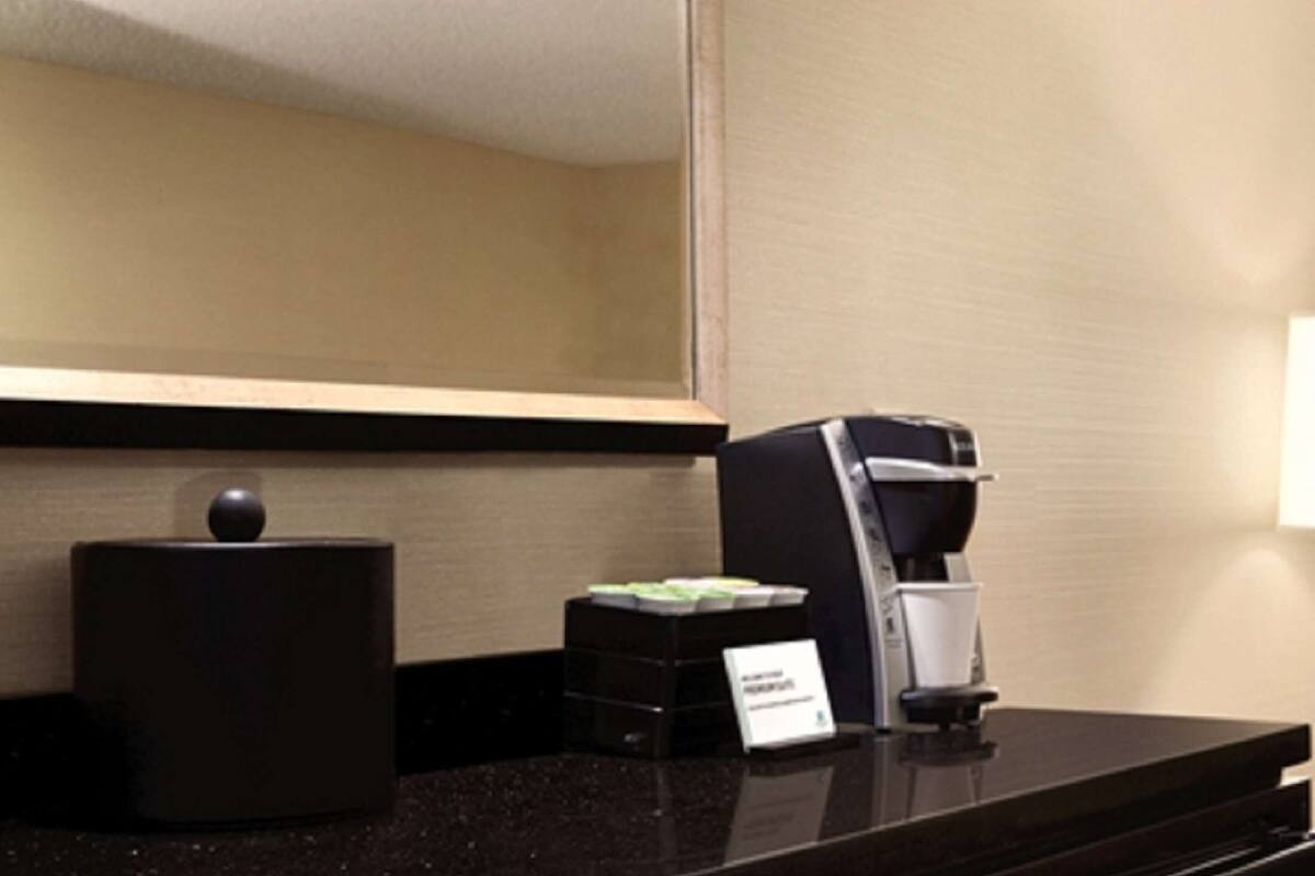 A hotel reception area with a coffee machine, a black container, and a small sign.