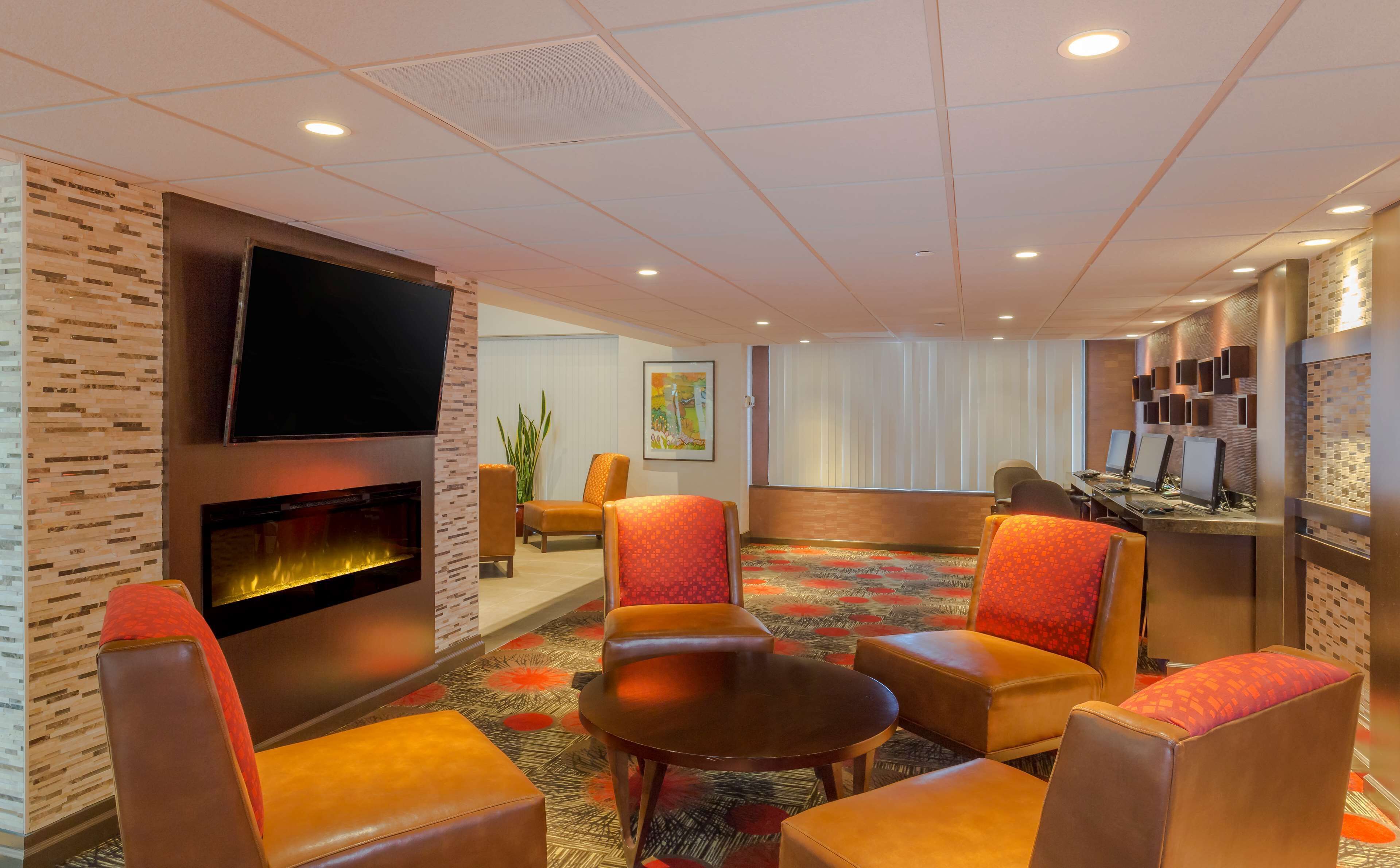 Un hall d’hôtel doté d’une cheminée, de sièges confortables, d’un téléviseur et d’un bureau avec des ordinateurs.