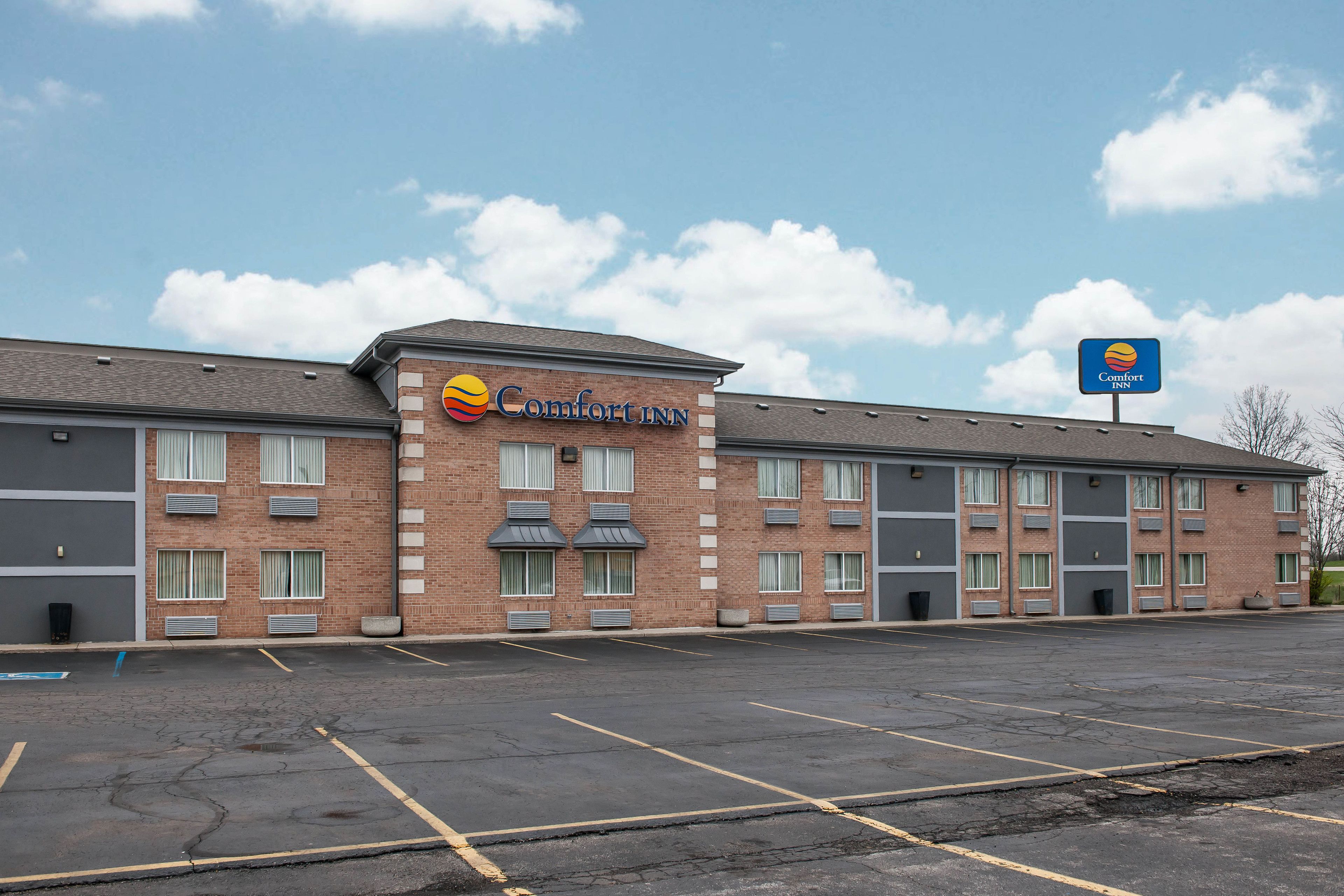 Ett Comfort Inn-hotell med en fasad av tegel, gott om parkeringsplatser och en klar himmel.