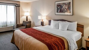 A hotel room with a large bed, two bedside lamps, a chair, a window with curtains, and a framed artwork on the wall. - Comfort Inn Indianapolis South I-65 (Indianapolis)