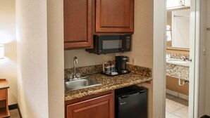 A compact kitchen with wooden cabinets, a built-in microwave, a coffee maker, and a dishwasher. - Comfort Inn Indianapolis South I-65 (Indianapolis)