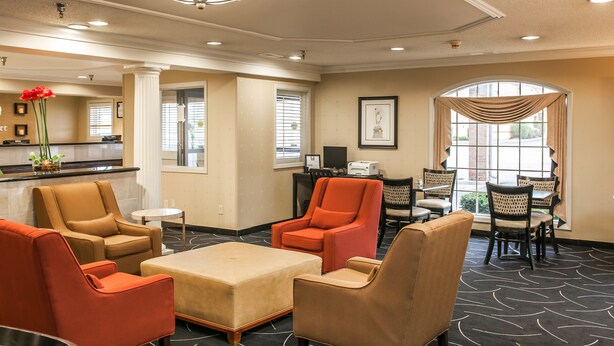 A hotel lobby with beige walls, a reception desk, and seating areas with orange and beige chairs. - Comfort Inn Indianapolis South I-65 (Indianapolis)