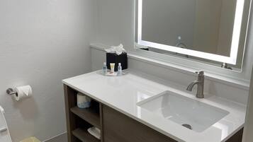 A bathroom with a white sink, a mirror, and a toilet.
